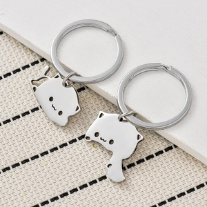 Detailed view of two polished stainless steel cat keychains with cute engraved faces