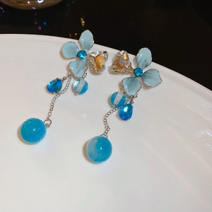 Détail de boucles d'oreilles fleurs bleues avec perles en cristal sur une assiette