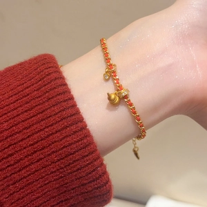 Vue détaillée du charm gourde plaqué or 24K et cœur sur bracelet tressé rouge