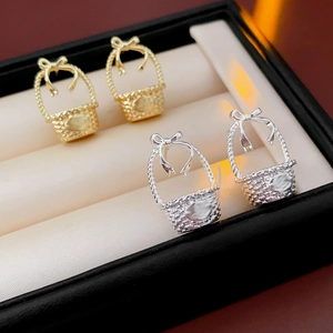 Macro view of gold and silver bow basket earrings displayed in a jewelry gift box