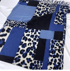 Close-up of winter leopard print scarf featuring blue color block and fringe details