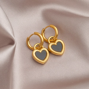 Golden heart-shaped hoop earrings with black enamel inlay on champagne silk background