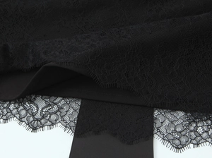 Close-up of intricate black lace floral embroidery and hollow-out detailing on the fabric