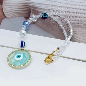 Close-up of blue Evil Eye heart pendant with gold clasp and faceted crystal beads
