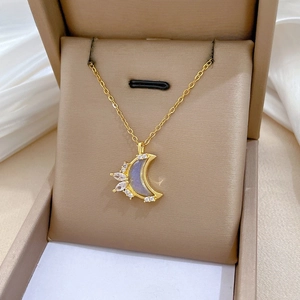 Close-up of golden crescent moon necklace with zircons on white silk background