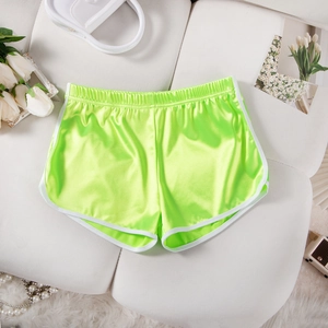 Close-up of neon green satin athletic shorts with white trim on a white sofa