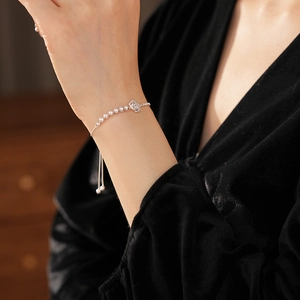 Détail d'un bracelet en argent avec perles et breloques fleuries sur velours noir