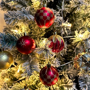 Detail of red and gold Christmas ball ornaments with star patterns on a snowy tree