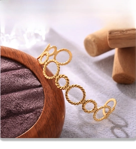 Detailed close-up of 18K gold plated twisted ring bracelet with PVD plating text