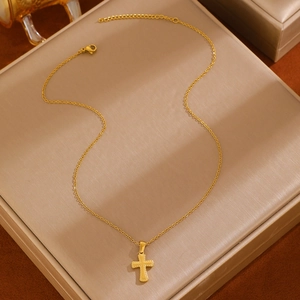 Detail of 18k gold plated stainless steel cross pendant on textured display cushion