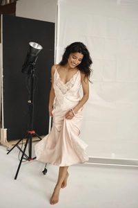 Detail of light pink satin slip dress with intricate white lace trim and V-neckline