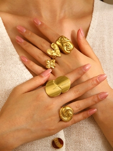 Detailed close-up of a five-piece set of chunky gold-toned rings on a model