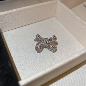 Macro shot of silver bow ear cuff set with crystals in a textured jewelry box
