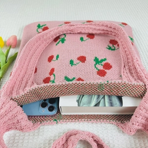 Detailed top view of pink knit tote bag showing cherry patterns and interior storage space