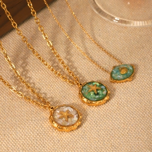 Detailed shot of 18K gold starfish and seashell pendants with crushed shell inlays