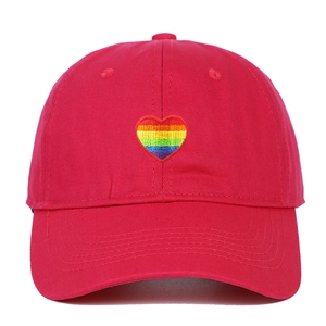 Detailed close-up of rainbow heart embroidery on bright red cotton twill baseball cap