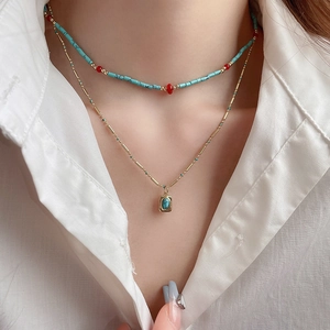 Detail of layered bohemian necklace featuring turquoise beads and a vintage gold pendant