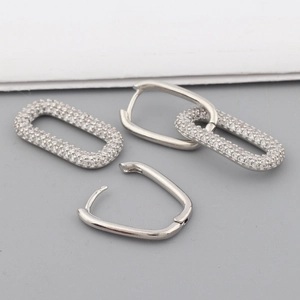 Macro view of silver geometric oval hoop earrings with sparkling cubic zirconia inlay
