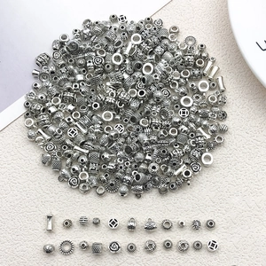 Assorted silver DIY jewelry beads and spacer charms in various patterns on white background