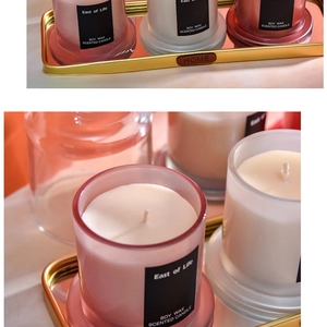 Candele profumate in cera di soia in vetri rosa e bianchi su un vassoio dorato