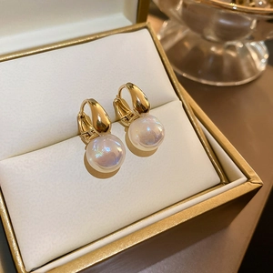 Détail de boucles d'oreilles créoles dorées avec perles blanches Aurora dans un écrin