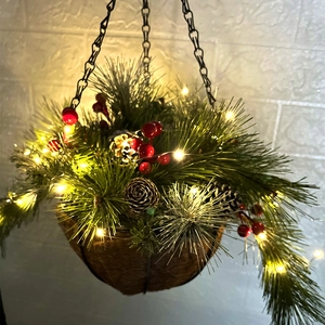 Gros plan sur un panier de Noël suspendu avec pommes de pin, baies et lumières LED chaudes