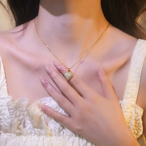 Elegant gold heart pendant necklace with shimmering cubic zirconia on model's neck