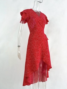 Detail of red polka dot wrap dress featuring ruffled cuffs and asymmetrical hem