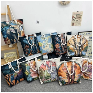 Detail of diverse canvas tote bags featuring colorful elephant embroidery and cotton rope handles