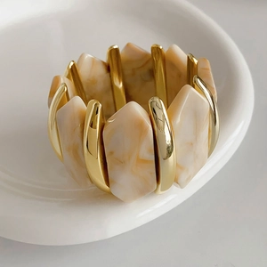 Détail du bracelet extensible en acrylique avec métal doré et texture marbre beige uni
