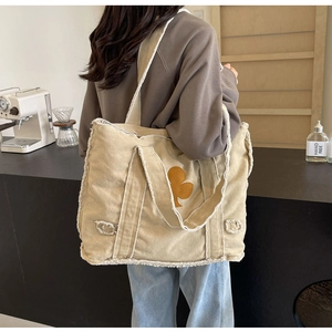 Detail of retro canvas tote bag featuring raw edges and tree patch in a coffee shop setting