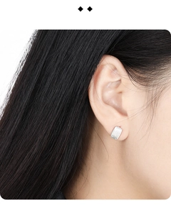 Macro view of S925 sterling silver geometric earring with brushed matte finish on earlobe