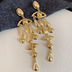 Macro detail of vintage gold oval tassel earrings with abstract eye and lip elements