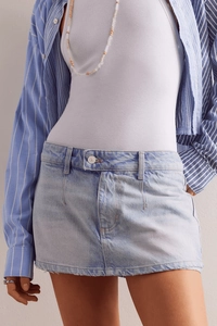 Dettaglio di minigonna in denim azzurro con orlo a taglio vivo e trama intrecciata