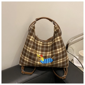 Detail of vintage brown plaid tote bag featuring a cute dachshund embroidery on a sofa