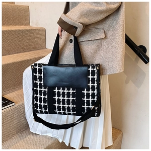 Detail of checkered tote bag with black PU leather flap and wide woven strap on stairs