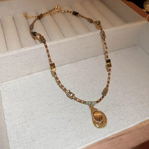 Detail of bohemian sun pendant necklace with tiger eye stone and beaded chain in vintage box