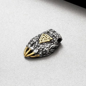 Détail macro du pendentif patte d'ours viking bicolore avec symbole Valknut en acier