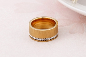 Dettaglio macro dell'anello in metallo spazzolato oro con una fila di cristalli bianchi