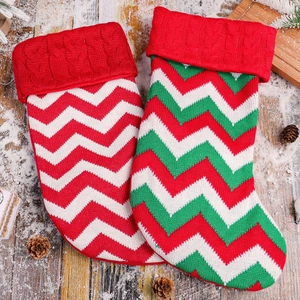 Set of two knitted Christmas stockings with wavy patterns on snow-covered wood