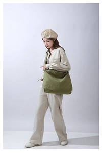 Dettaglio di una grande borsa a tracolla in tela di cotone verde indossata da una modella