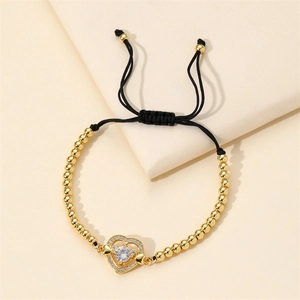 Bracelet cœur perlé doré avec zircone micro-pavé sur un support d'exposition beige