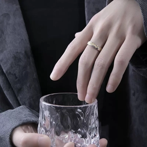 Men's two-tone gold and silver textured ring worn by a model holding a glass
