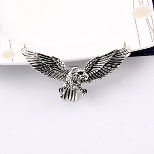 Close-up of vintage silver eagle brooch with green gem eye and detailed wing textures