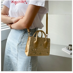 Detail of beige straw bag with floral embroidery and brown faux leather side panels