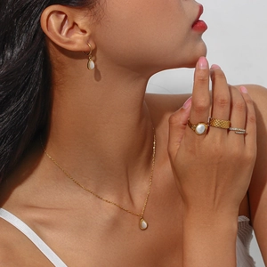 Gold-plated jewelry set with teardrop opal pendants on model neck, ears and hands