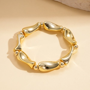 Detail of gold geometric bracelet featuring fluid streamline links and polished metal beads