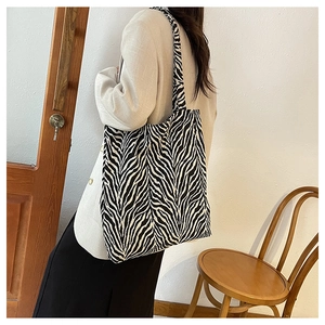 Minimalist black and white zebra print canvas tote bag shown on model's shoulder