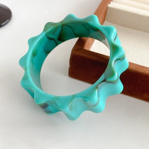 Detail of green marble resin bangle with wavy edges and artistic swirl pattern