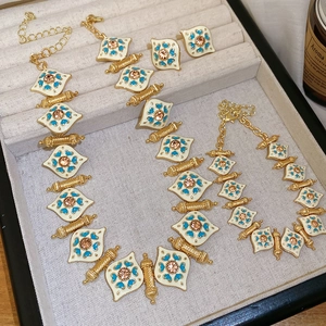 Vintage gold jewelry set with enamel patterns and peach gems in a velvet gift box